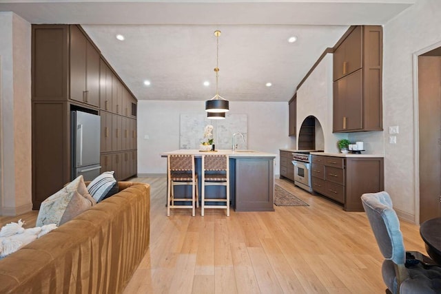 kitchen with light wood-style floors, a kitchen bar, appliances with stainless steel finishes, a sink, and light countertops