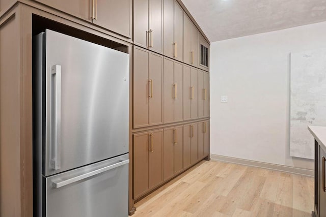 kitchen featuring visible vents, baseboards, light countertops, freestanding refrigerator, and light wood finished floors