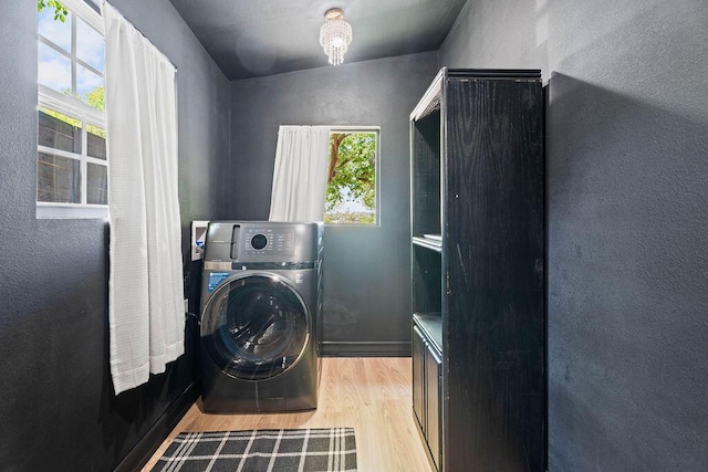 washroom featuring washer / clothes dryer, light wood-style floors, laundry area, and a textured wall