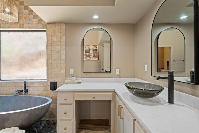 full bath with a freestanding bath, recessed lighting, and vanity