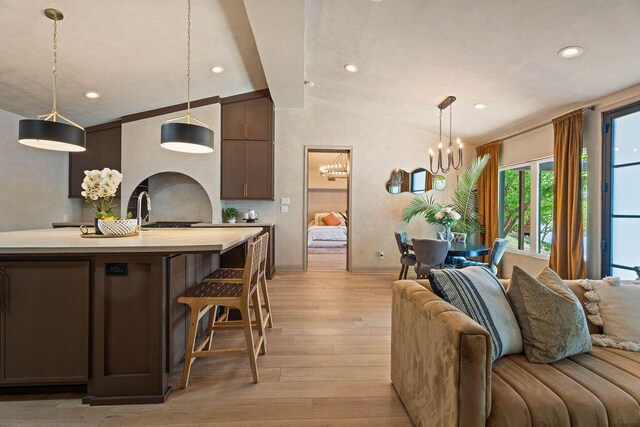 living area with a notable chandelier, baseboards, vaulted ceiling, recessed lighting, and light wood-style floors