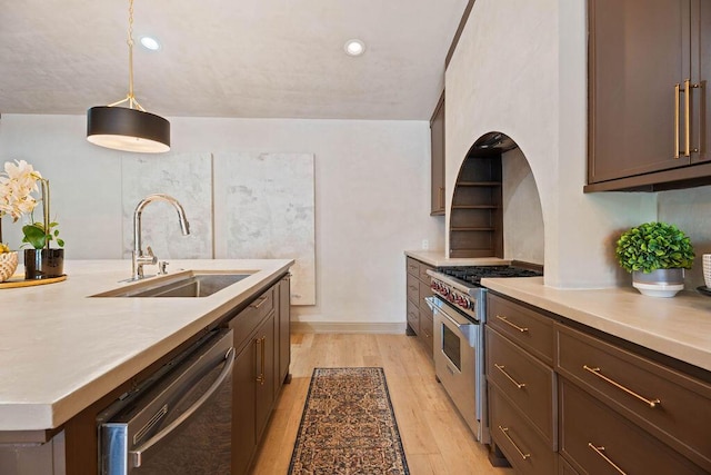 kitchen with hanging light fixtures, a sink, light countertops, light wood-style floors, and stainless steel appliances