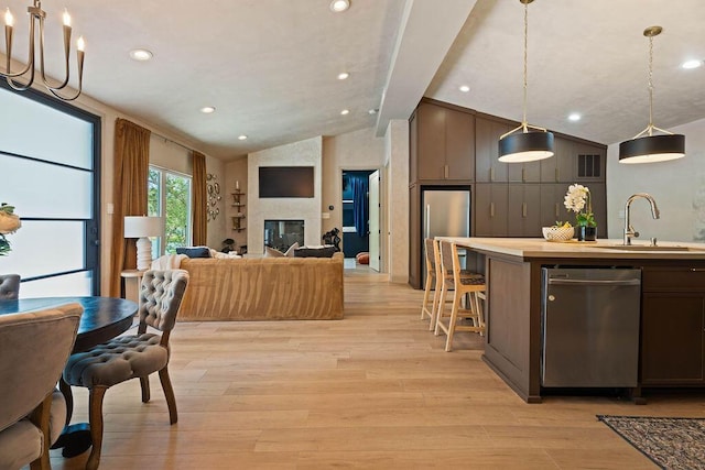 interior space with light wood-type flooring, a sink, vaulted ceiling with beams, stainless steel appliances, and open floor plan