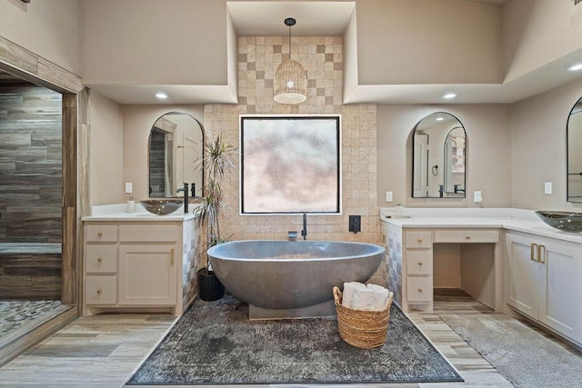 full bath featuring a freestanding bath, wood finished floors, a sink, and recessed lighting