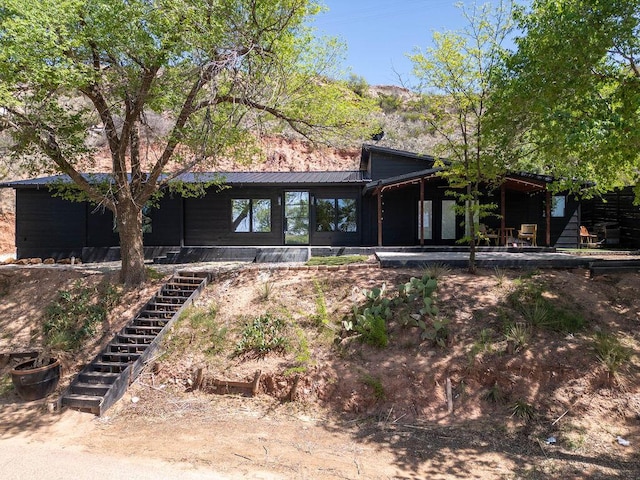 back of property featuring stairs, metal roof, and a sunroom