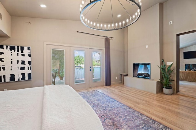 bedroom featuring recessed lighting, wood finished floors, french doors, access to exterior, and a glass covered fireplace