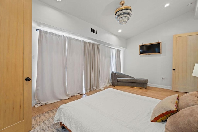 bedroom featuring wood finished floors, visible vents, baseboards, and vaulted ceiling