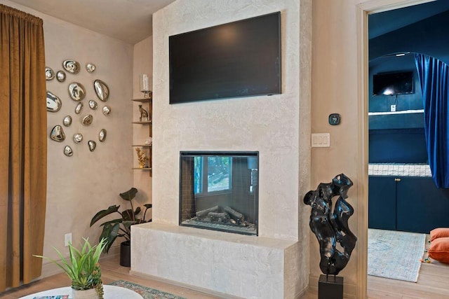 living room featuring a high end fireplace, built in shelves, and wood finished floors