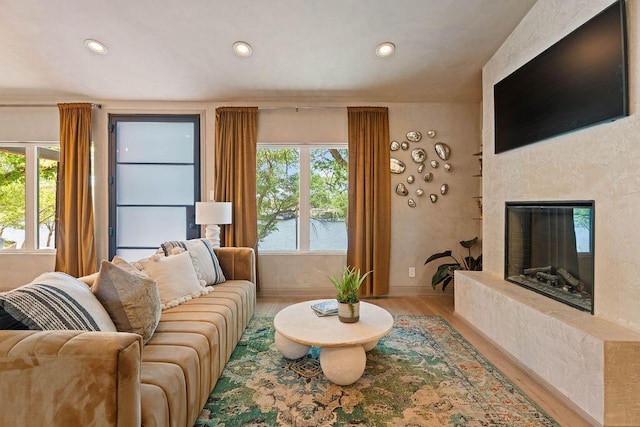living room featuring recessed lighting, a premium fireplace, and wood finished floors