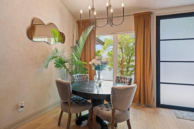 dining room with a chandelier, light wood finished floors, and baseboards