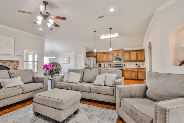 living room featuring hardwood / wood-style flooring, ceiling fan with notable chandelier, and ornamental molding