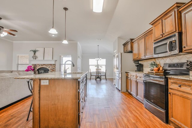 kitchen with decorative light fixtures, backsplash, a kitchen breakfast bar, stainless steel appliances, and a center island with sink