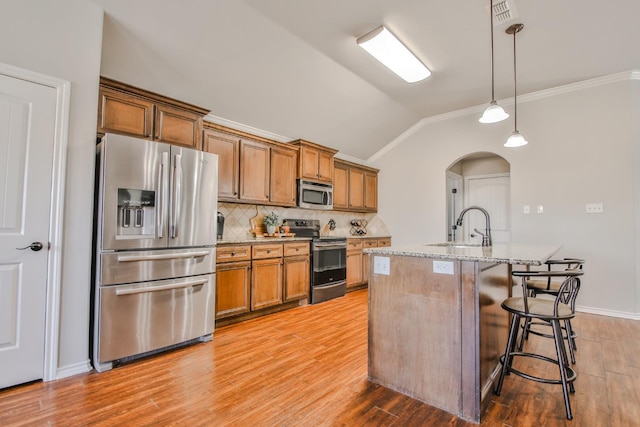 kitchen featuring decorative light fixtures, sink, a kitchen island with sink, stainless steel appliances, and light stone countertops