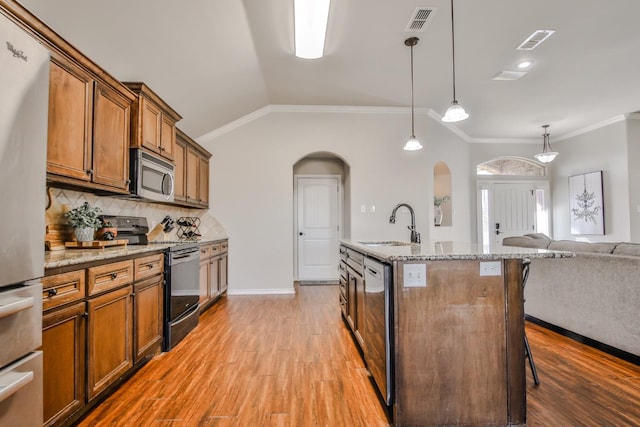 kitchen featuring sink, appliances with stainless steel finishes, an island with sink, a kitchen bar, and decorative light fixtures