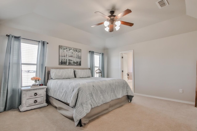 carpeted bedroom with ceiling fan, ensuite bathroom, a raised ceiling, and vaulted ceiling