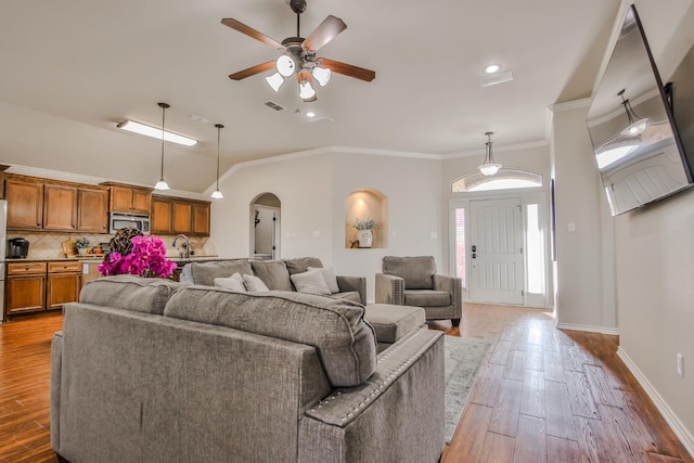 living room with hardwood / wood-style flooring, lofted ceiling, ornamental molding, and ceiling fan