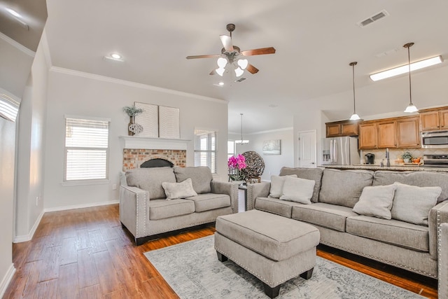 living room with crown molding, a fireplace, dark hardwood / wood-style floors, and ceiling fan