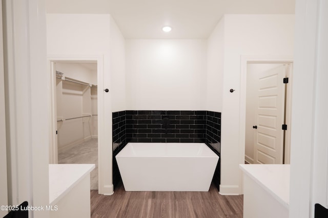 5005 Prentiss Ave, Lubbock, TX 79407 - bathroom featuring a freestanding tub, vanity, a walk in closet, and wood finished floors