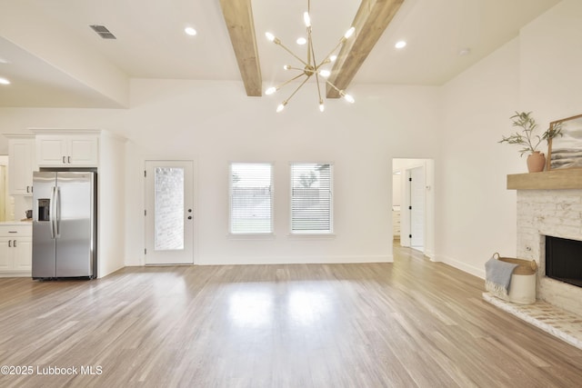 5005 Prentiss Ave, Lubbock, TX 79407 - unfurnished living room featuring light wood-style flooring, a chandelier, beam ceiling, and a stone fireplace
