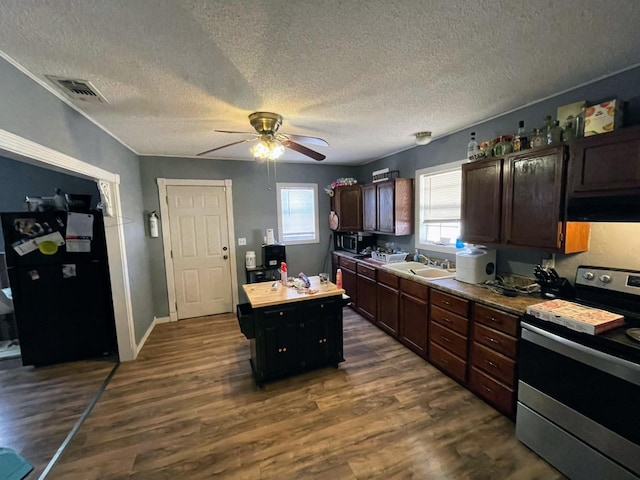 kitchen with appliances with stainless steel finishes, range hood, a center island, dark wood-type flooring, and a textured ceiling