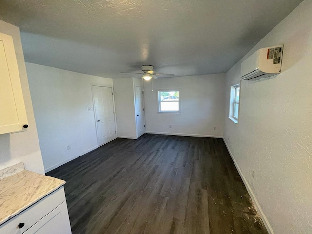 interior space featuring ceiling fan, dark hardwood / wood-style floors, a textured ceiling, and an AC wall unit