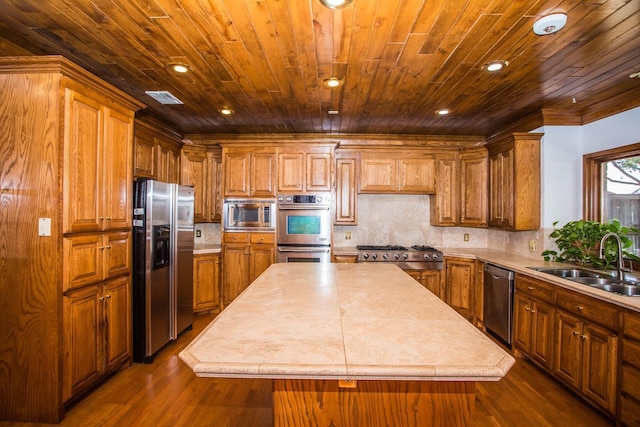 kitchen with appliances with stainless steel finishes, dark hardwood / wood-style floors, sink, backsplash, and a center island