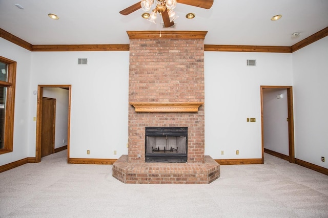 unfurnished living room with ornamental molding, a brick fireplace, light carpet, and ceiling fan