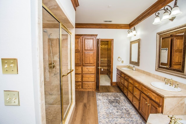 bathroom with ornamental molding, hardwood / wood-style floors, vanity, and a shower with shower door