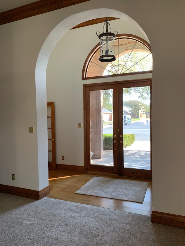 carpeted foyer with french doors, a towering ceiling, and an inviting chandelier