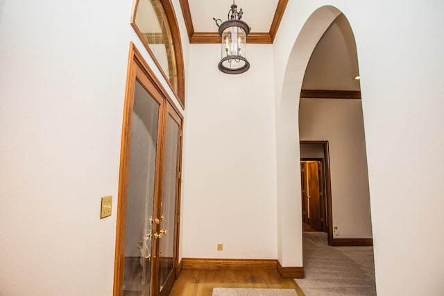 hall with a high ceiling, ornamental molding, and light hardwood / wood-style floors