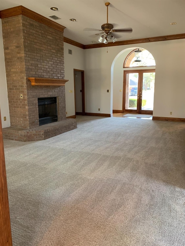 unfurnished living room featuring ceiling fan, a fireplace, carpet floors, ornamental molding, and french doors