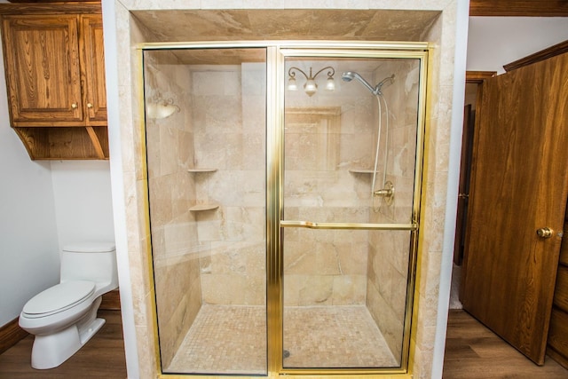 bathroom featuring hardwood / wood-style floors, a shower with shower door, and toilet