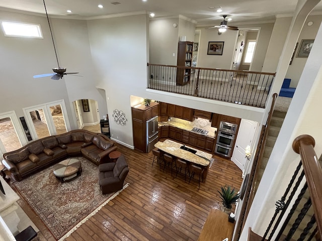 4009 109th St, Lubbock, TX 79423 - living room with ceiling fan, dark wood-style flooring, crown molding, a high ceiling, and arched walkways