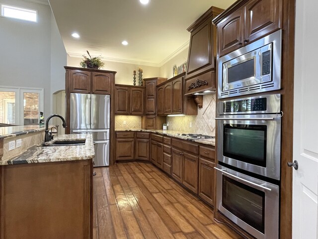 4009 109th St, Lubbock, TX 79423 - kitchen featuring stainless steel appliances, crown molding, decorative backsplash, light stone countertops, and wood finished floors