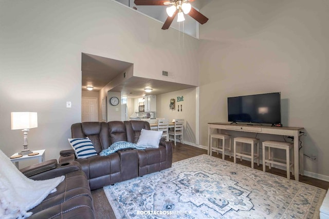 living room featuring ceiling fan, wood-type flooring, and a towering ceiling