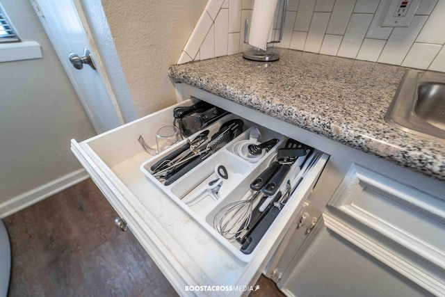 details featuring light stone counters, sink, decorative backsplash, and dark hardwood / wood-style floors