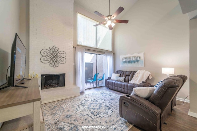 living room featuring wood-type flooring, high vaulted ceiling, ceiling fan, and a fireplace