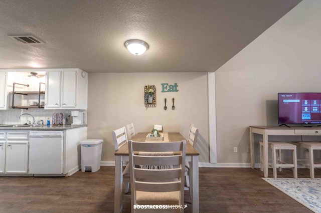 dining room featuring sink, dark wood-type flooring, and a textured ceiling