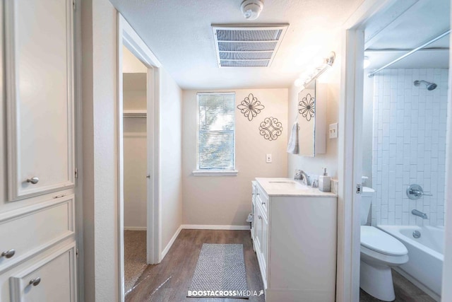 full bathroom with tiled shower / bath, vanity, toilet, and hardwood / wood-style floors