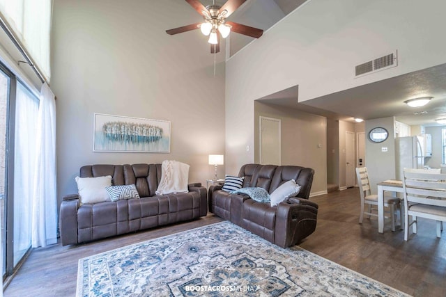 living room with wood-type flooring, ceiling fan, and a high ceiling