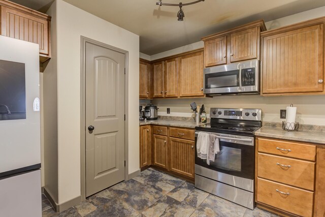 6208 21st St, Lubbock, TX 79407 - kitchen featuring brown cabinetry, baseboards, and stainless steel appliances