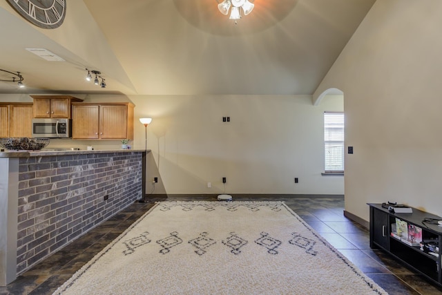 6208 21st St, Lubbock, TX 79407 - unfurnished living room featuring vaulted ceiling, rail lighting, arched walkways, and baseboards