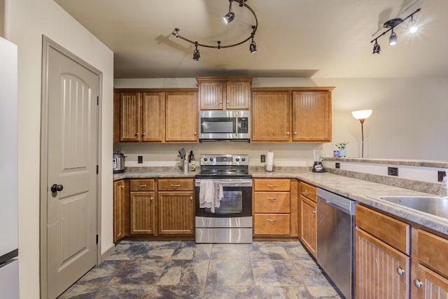 6208 21st St, Lubbock, TX 79407 - kitchen featuring brown cabinetry, a sink, rail lighting, light countertops, and appliances with stainless steel finishes