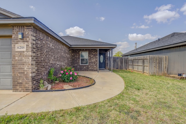 6208 21st St, Lubbock, TX 79407 - exterior space with fence, an attached garage, brick siding, a patio, and a lawn