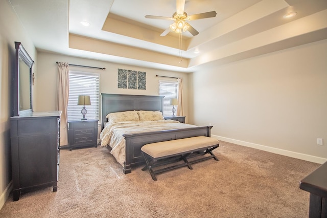 bedroom featuring a tray ceiling, light colored carpet, and ceiling fan