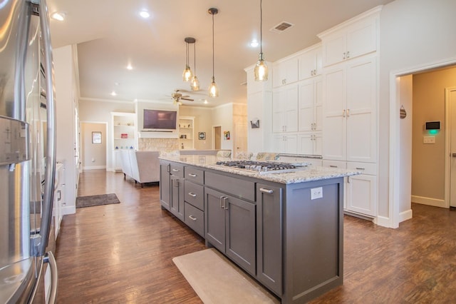 kitchen with white cabinetry, hanging light fixtures, stainless steel appliances, light stone counters, and an island with sink