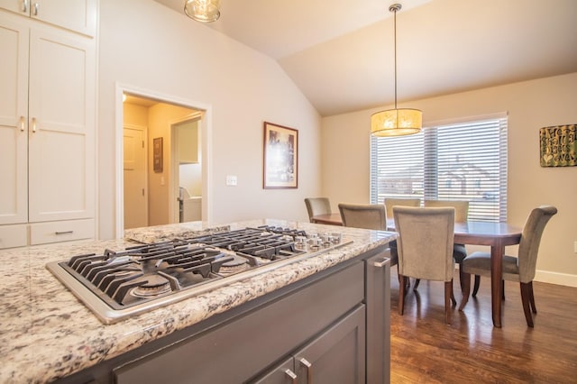 kitchen with decorative light fixtures, lofted ceiling, dark hardwood / wood-style flooring, stainless steel gas cooktop, and light stone counters