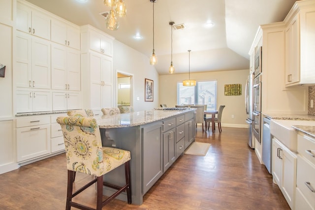 kitchen featuring gray cabinets, a kitchen island, pendant lighting, white cabinets, and a kitchen bar