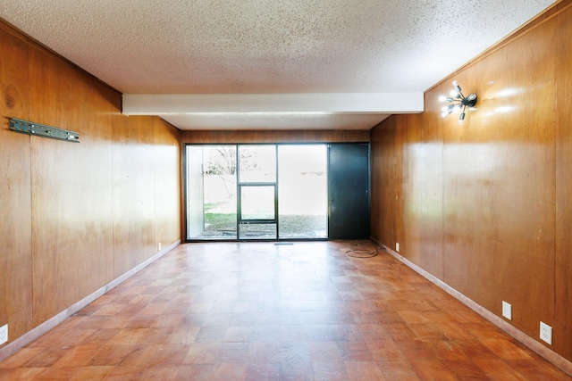 empty room featuring wooden walls and a textured ceiling