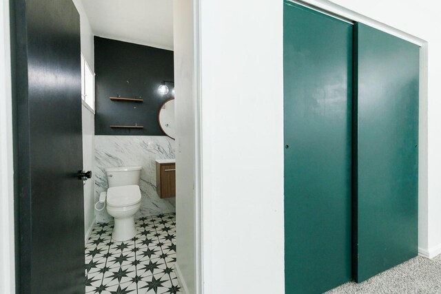 bathroom with toilet and tile walls